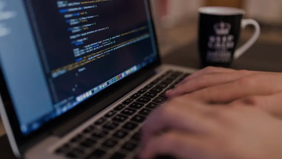 Hands typing code on a laptop