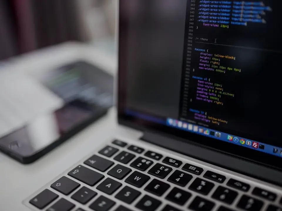 Laptop on a desk showing source code