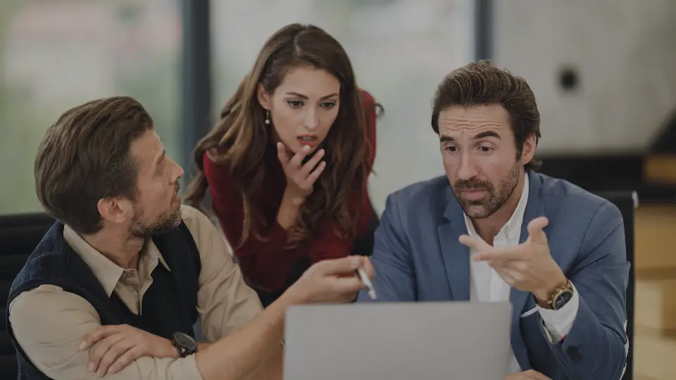 Three people discussing work around a laptop