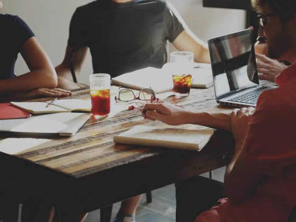 A project team planning around a table with laptops and notes