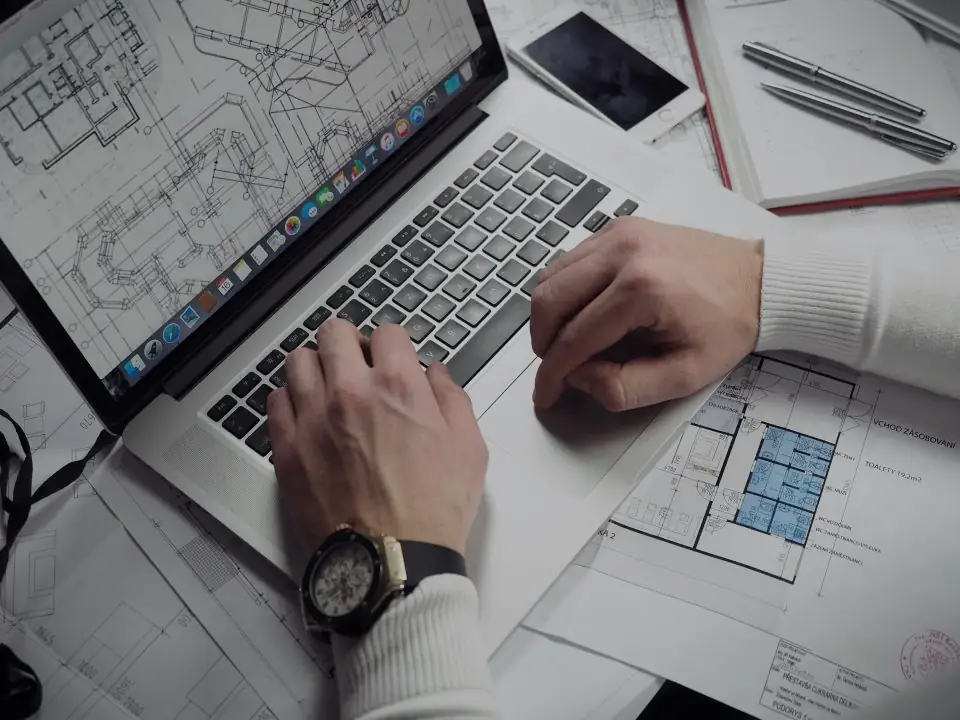 Hands on a laptop next to printed wireframes